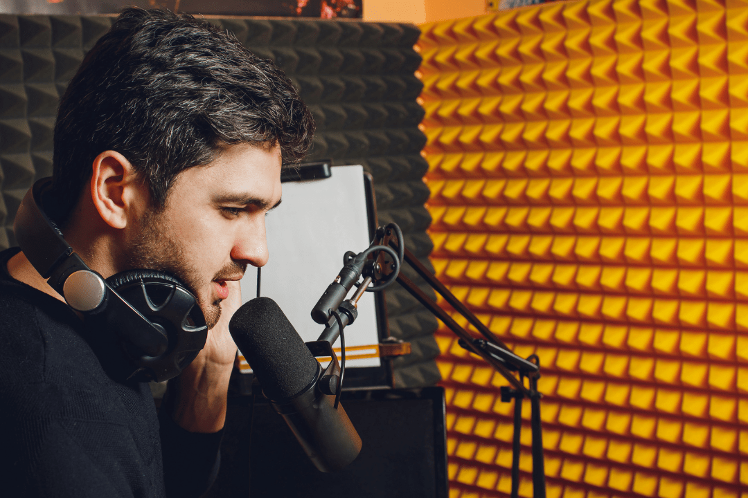 Podcaster mit Kopfhörern und Podcast-Mikrofon nimmt einen Business-Podcast im Tonstudio auf.